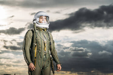 Mann posiert als Astronaut gekleidet mit dramatischen Wolken im Hintergrund - DAMF00094