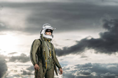 Mann posiert als Astronaut gekleidet mit dramatischen Wolken im Hintergrund - DAMF00095