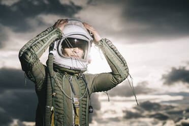 Mann posiert als Astronaut gekleidet mit dramatischen Wolken im Hintergrund - DAMF00096