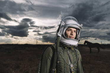 Mann posiert als Astronaut gekleidet mit dramatischen Wolken im Hintergrund - DAMF00098