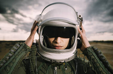 Man with astronaut helmet, dramatic clouds in the background - DAMF00099