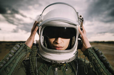 Mann mit Astronautenhelm, dramatische Wolken im Hintergrund - DAMF00099