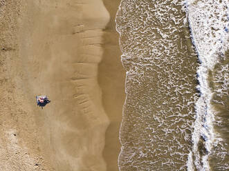 Spanien, Sitges, Luftaufnahme von Mutter und Tochter am Sandstrand liegend - PSIF00329