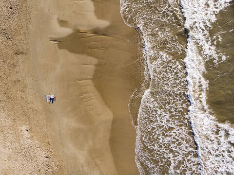 Spanien, Sitges, Luftaufnahme von Mutter und Tochter am Sandstrand liegend, lizenzfreies Stockfoto