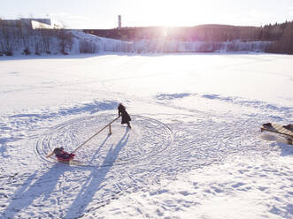 Finnland, Kuopio, hoher Blickwinkel von Mutter und Tochter beim Spielen im Schnee - PSIF00332