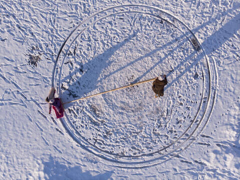 Finnland, Kuopio, Blick von oben auf Mutter und Tochter beim Spielen im Schnee, lizenzfreies Stockfoto