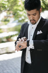 Young businessman in the city checking the time - JPIF00172