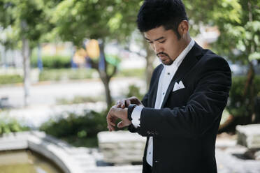 Young businessman in the city checking the time - JPIF00173
