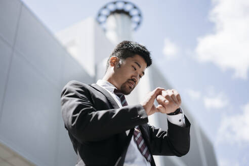 Young businessman in the city checking the time - JPIF00181