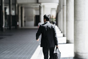 Rear view of young businessman walking in the city - JPIF00186