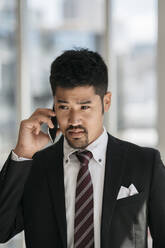 Portrait of young businessman talking on the phone - JPIF00202