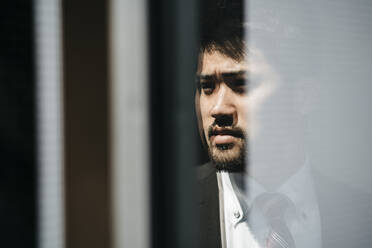 Porträt eines jungen Geschäftsmannes, der sich im Fenster spiegelt - JPIF00208