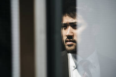 Portrait of young businessman reflected in the window - JPIF00208