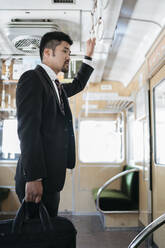 Junger Geschäftsmann in einem Zug - JPIF00227
