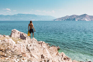 Kroatien, Krk, Mann steht auf einer Felsformation und schaut aufs Meer - WVF01431