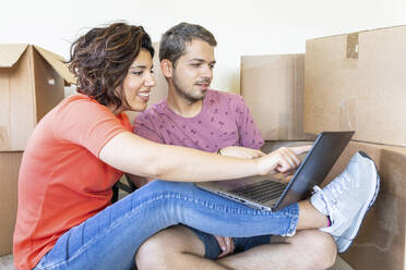Happy couple moving into new home using laptop - WPEF01928