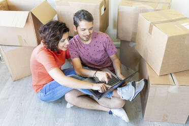 Happy couple moving into new home using laptop - WPEF01929