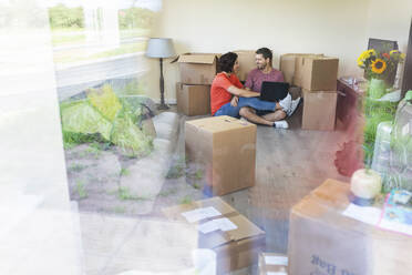 Happy couple moving into new home using laptop - WPEF01930