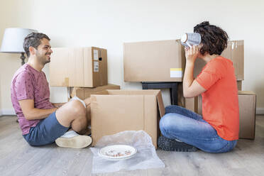 Happy couple moving into new home unpacking cardboard box - WPEF01936