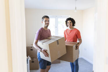 Porträt eines glücklichen Paares, das mit Kartons in ein neues Haus einzieht - WPEF01952