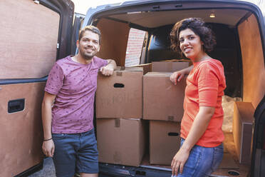 Porträt eines lächelnden Paares an einem Lieferwagen mit Pappkartons - WPEF01961