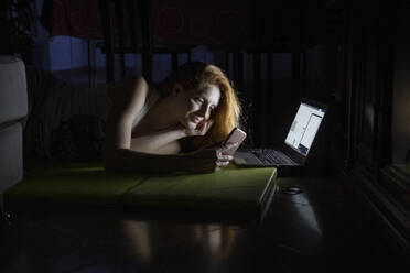 Junge Frau benutzt Laptop und Handy spät in der Nacht - AFVF03972