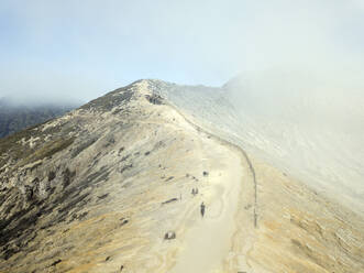 Indonesien, Java, Person geht zu einer abgelegenen Hütte mit Blick auf den Vulkan Ijen - KNTF03564