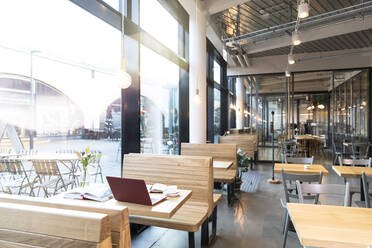 Laptop and books on table in a modern cafe - FKF03618