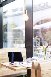 Laptop und Bücher auf einem Tisch in einem modernen Cafe - FKF03622