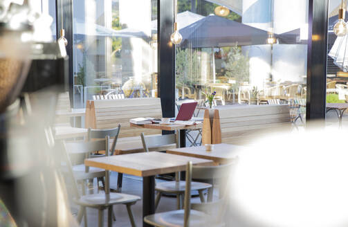 Laptop and books on table at a modern cafe - FKF03624