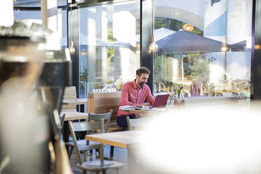 Junger Mann mit Laptop in einem Café - FKF03625