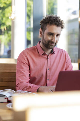 Junger Mann mit Laptop in einem Café, lizenzfreies Stockfoto