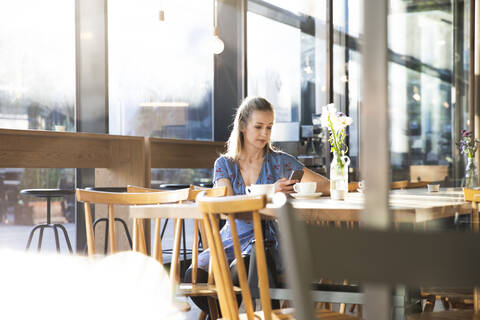 Frau benutzt Mobiltelefon in einem Cafe, lizenzfreies Stockfoto