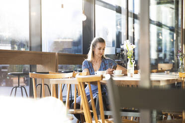 Frau benutzt Mobiltelefon in einem Cafe - FKF03629