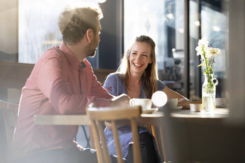 Lachende Frau und Mann im Gespräch am Tisch in einem Café, lizenzfreies Stockfoto