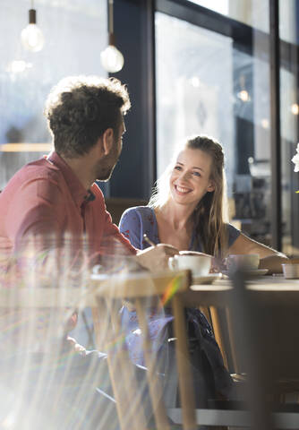 Lächelnde Frau und Mann unterhalten sich am Tisch in einem Cafe, lizenzfreies Stockfoto