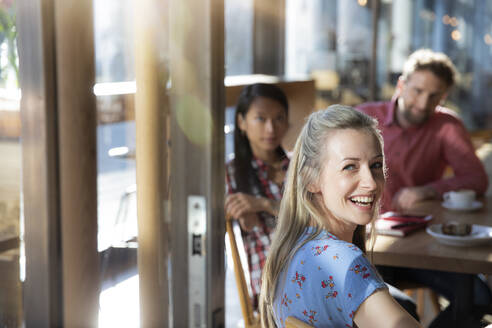 Portrait of happy woman with friends in a cafe - FKF03643
