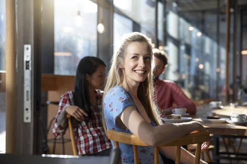 Portrait of smiling woman with friends in a cafe - FKF03644