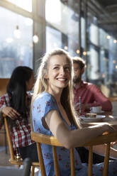 Porträt einer lächelnden Frau mit Freunden in einem Cafe - FKF03645
