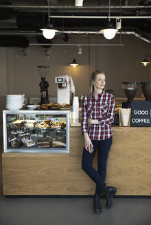 Frau steht an der Theke eines Cafés und schaut sich um - FKF03654