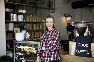 Porträt einer lächelnden Frau an der Theke eines Cafés - FKF03655