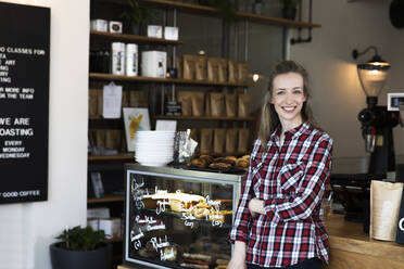 Porträt einer lächelnden Frau an der Theke eines Cafés - FKF03656