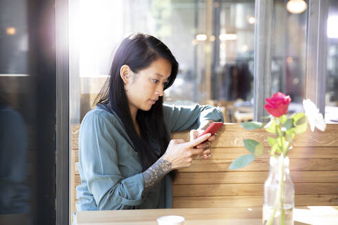 Woman using cell phone in a cafe - FKF03658