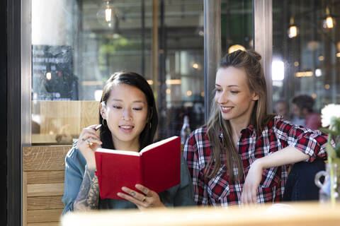 Zwei Frauen mit Buch in einem Cafe, lizenzfreies Stockfoto