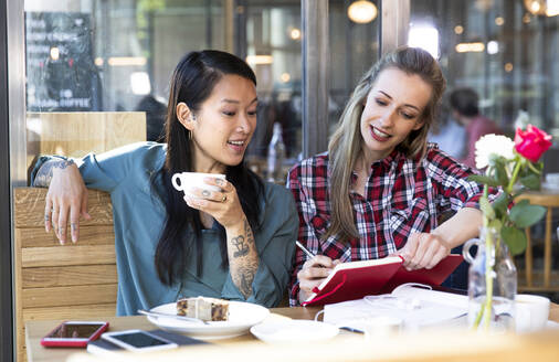 Zwei Frauen mit Buch in einem Cafe - FKF03662