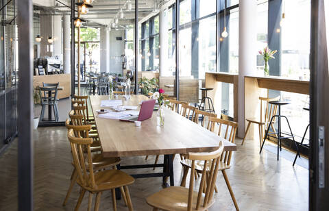 Laptop und Dokumente auf einem Tisch in einem modernen Café, lizenzfreies Stockfoto