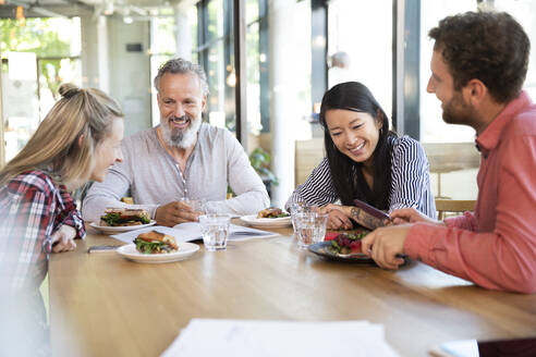 Happy casual business people having business lunch in a cafe - FKF03693