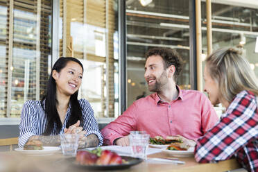 Glückliche Freunde beim Mittagessen in einem Cafe - FKF03694