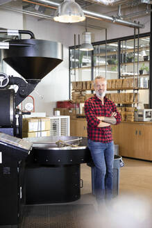 Portrait of confident mature man in a coffee roastery - FKF03696