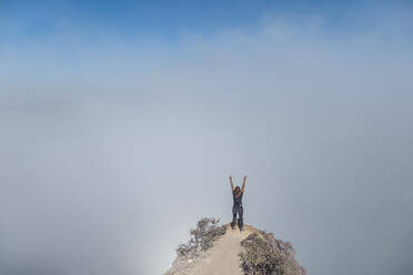 Woman with raised arms on view point, Ijen volcano, Java, Indonesia - KNTF03573